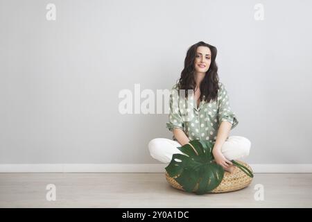 Happy brunette pregnant woman holding monstera leaf Banque D'Images