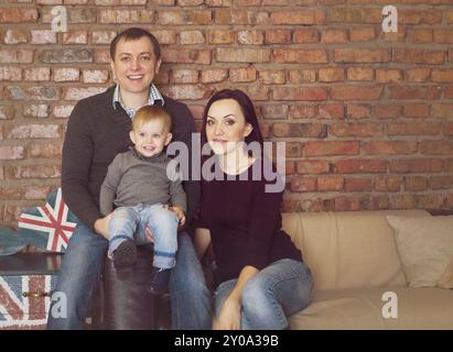 Heureux jeune père, mère et cute baby girl sur brick wall background Banque D'Images