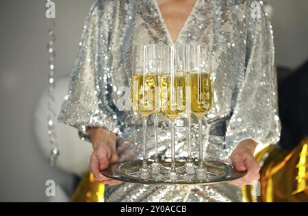 Close up de la jeune femme portant robe de cocktail avec le bac de la verres de champagne brillant sur fond noir, blanc, les ballons d'or et d'argent backgroun Banque D'Images