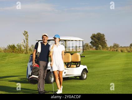 Jeune couple sportif jouer au golf sur un parcours de golf. Debout près de l'golfcar Banque D'Images