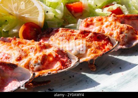 moules cuites au four avec du caviar masago et du fromage sur une assiette blanche avec du citron Banque D'Images
