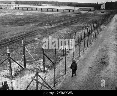 Des soldats américains patrouillent le périmètre du camp de concentration de Wöbbelin nouvellement libéré. Les SS ont ouvert Wöbbelin en février 1945 pour héberger des prisonniers des camps de concentration qu'ils avaient évacués d'autres camps pour empêcher leur libération par les Alliés. Le camp a été libéré le 2 mai 1945. Banque D'Images