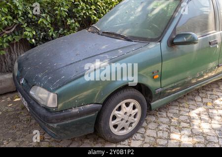 Vieille renault 19 rti verte avec sa carrosserie recouverte de poussière, garée sur une rue pavée de pierres Banque D'Images