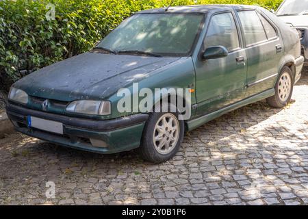 Vieille, sale et verte renault 19 rti est stationnée dans une rue pavée, montrant des signes de son âge et de son utilisation Banque D'Images