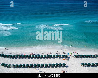 Parasols et chaises alignés le long d'un front de mer tandis que les vagues douces roulent de l'océan Banque D'Images