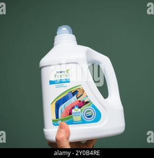 Berlin, Allemagne - Oct, 22, 2019 : une main tenant une bouteille de détergent à lessive concentré liquide Amway Home SA8 sur fond vert, mettant en vedette l emballage du produit et le message de durabilité Banque D'Images