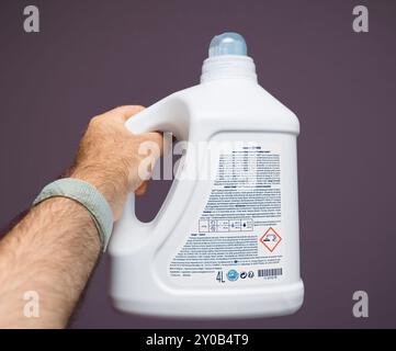 Berlin, Allemagne - Oct, 22, 2019 : une main tenant le dos d'une bouteille de détergent à lessive concentré liquide Amway Home SA8, montrant les informations détaillées sur le produit sur un fond violet Banque D'Images