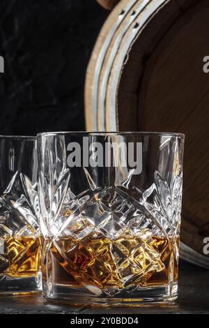 Whisky dans un verre avec un tonneau. Whisky Bourbon et un fût sur fond sombre, un élégant gros plan, photographie culinaire Banque D'Images