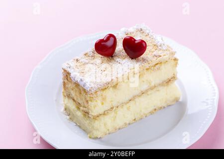 Mille feuille français avec crème vanille gâteau décoré avec des coeurs sur fond rose pour la Saint-Valentin Banque D'Images