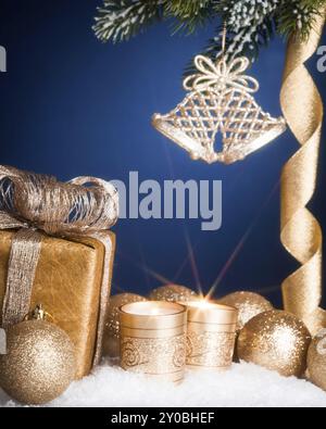 Décorations d'arbre de Noël et bougies allumées dans la neige sur fond bleu foncé. La photo a été prise avec un filtre à effet étoile Banque D'Images