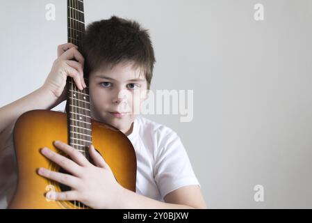 Teenage Boy joue de la guitare acoustique tout en se relaxant sur une chaise de patio Banque D'Images