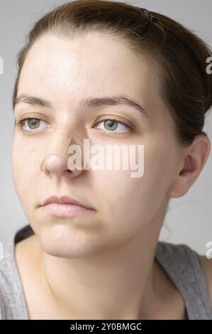 Jeune femme avec pansement sur son nez Banque D'Images