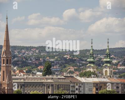 Vue sur la ville avec plusieurs tours et bâtiments en face d'une colline boisée, budapest, danube, hongrie Banque D'Images