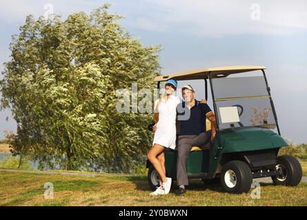 Jeune couple sportif jouer au golf sur un parcours de golf. Debout près de l'golfcar Banque D'Images