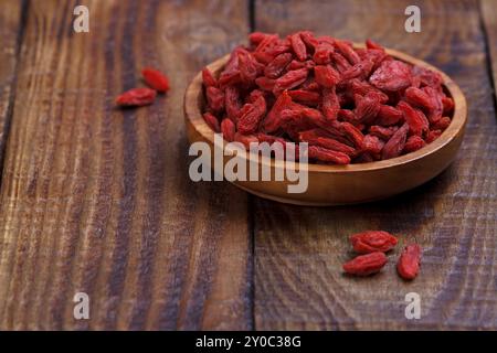 Baies de Goji dans un bol en bois sur une vieille planche rustique, mise au point sélective, macro Banque D'Images