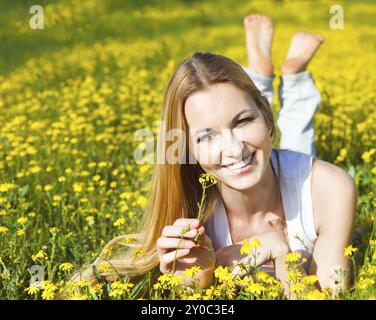 Belle jeune fille blonde portant sur le champ de fleurs Daisy. Portrait en extérieur. Concept d'été Banque D'Images