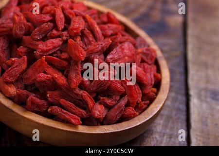 Baies de Goji dans un bol en bois sur une vieille planche rustique, mise au point sélective, macro Banque D'Images