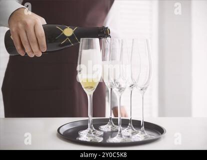 L'uniforme professionnel waiter pouring champagne dans une flûte. DOF. La lumière naturelle. Photo en mouvement Banque D'Images