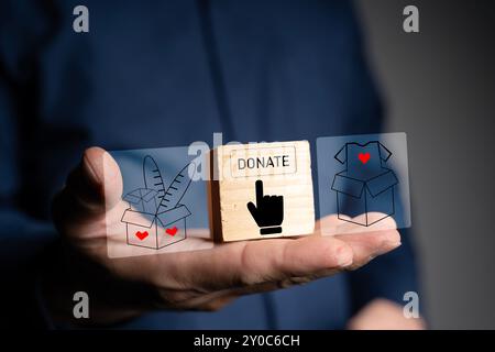 Concept de don. Boîte de don avec des vêtements de don sur un fond en bois. Charité. Aide aux personnes dans le besoin. Faites du bénévolat avec une boîte de dons avec des vêtements Banque D'Images
