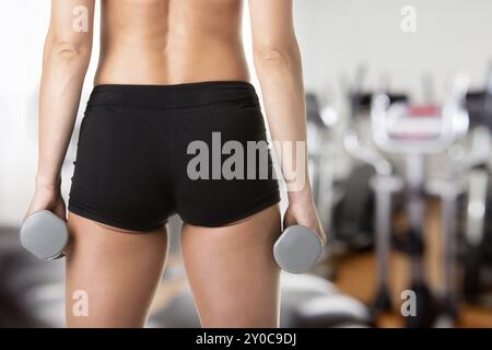 Close up de l'arrière d'un fit woman working out with dumbbells, dans une salle de sport Banque D'Images