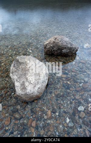 Une image en gros plan de deux rochers dans l'eau calme du lac Banque D'Images