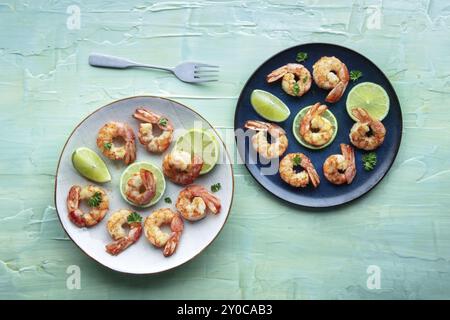 Crevettes, top shot sur une table bleu sarcelle. Crevettes grillées avec citron vert, plat de fruits de mer épicé, photographie culinaire Banque D'Images