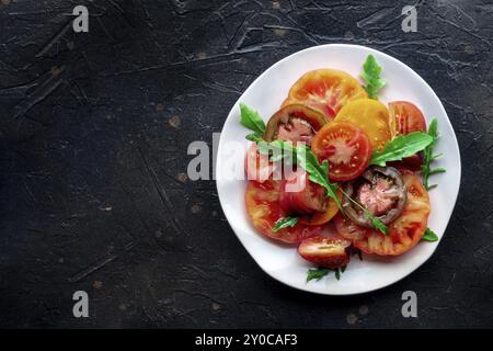 Salade de tomates fraîches et roquette. Une variété de tomates de différentes sortes, tirées d'en haut avec des feuilles de roquette. Nourriture d'été saine, tiré du haut w Banque D'Images