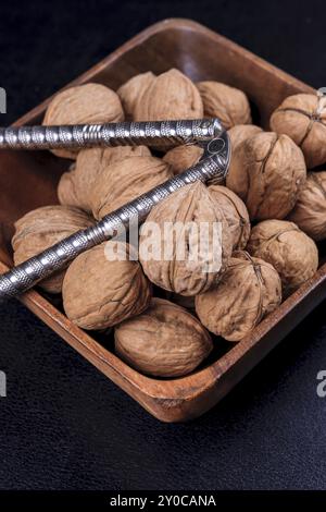 Une photo en gros plan de noix non coques et un casse-noix dans un bol en bois Banque D'Images