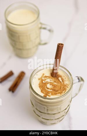 Une vue rapprochée d'en haut de verres de lait de poule à la cannelle et un bâton de cannelle dans le plus proche Banque D'Images