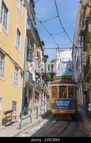 Un tramway jaune-bleu traverse une rue étroite devant des bâtiments historiques colorés par une journée ensoleillée, Tram, ligne 28, Carros electricos de Lisboa, Electri Banque D'Images