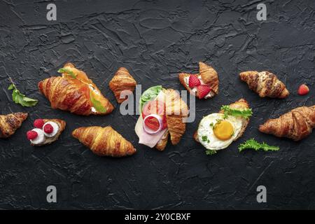 Variété sandwich croissant. Différents croissants farcis, top shot sur fond de pierre sombre. Rouleaux remplis de jambon, saumon, oeuf, etc., photograp alimentaire Banque D'Images