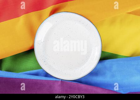 Concept alimentaire gay. Une assiette, plat de dessus plan sur la texture du drapeau arc-en-ciel LGBTQ, un motif d'invitation de dîner Banque D'Images