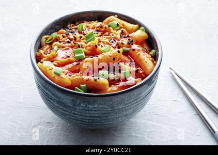 Rabokki, tteokbokki ou topokki avec ramen, cuisine de rue coréenne, gâteaux de riz épicés à la sauce gochujang au poivron rouge, avec baguettes, photographie culinaire Banque D'Images