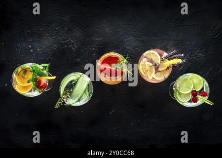 Cocktails raffinés avec fruits frais. Gin et boissons toniques avec de la glace lors d'une fête, sur un fond noir, plan à plat au-dessus, photographie culinaire Banque D'Images