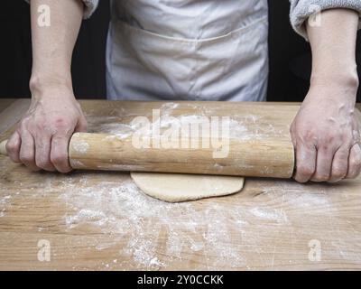 Une photo conceptuelle de rouler de la pâte sur une planche à découper à l'aide d'un rouleau à pâtisserie Banque D'Images