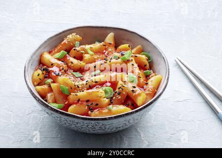 Tteokbokki ou topokki, cuisine de rue coréenne, gâteaux de riz épicés en sauce gochujang au poivron rouge, avec baguettes, photographie culinaire Banque D'Images