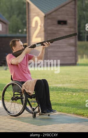 Un vieil homme en fauteuil roulant s'entraîne dans un champ de tir, visant avec précision et mise au point Banque D'Images