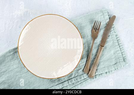 Une assiette blanche vide avec un bord doré, avec une fourchette et un couteau, plan de pose à plat au-dessus, le concept de dîner, photographie culinaire, photographie culinaire Banque D'Images