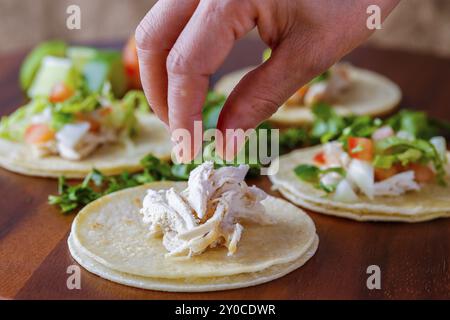 Mettre des morceaux de poulet sur un petit taco de rue sur une planche de bois Banque D'Images