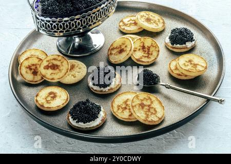 Blinis au caviar noir et fromage à la crème, sur un plat festif, mini crêpes, un élégant apéritif Banque D'Images