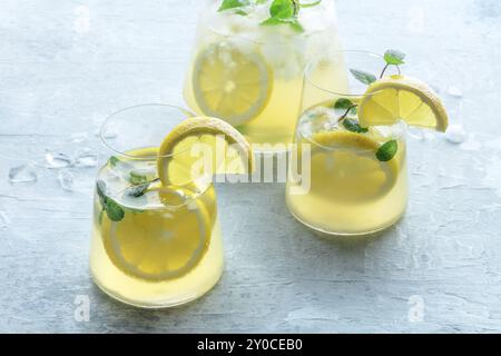 Limonade à la menthe. Boisson à l'eau de citron avec glace. Deux verres et un pichet sur fond pastel. Boisson détox. Cocktail maison frais Banque D'Images