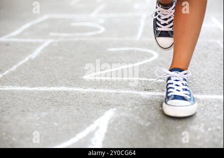 Jouer à la marelle sur l'aire de jeux pour enfants en plein air, les enfants Activités de plein air Banque D'Images