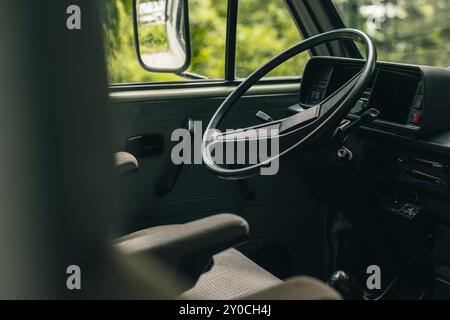 Position des conducteurs d'une vieille fourgonnette vintage. Grand volant en plastique et sièges de capitaine visibles dans une fourgonnette des années 80 Vue du volant, des commandes, Banque D'Images