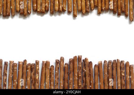 Bâtonnets de bretzel salés en deux rangées sur fond blanc Banque D'Images