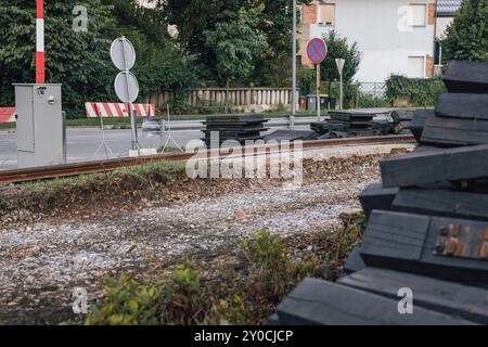 Rénovation de passages à niveau. Barrières sur les passages à niveau pour piétons, avec panneaux de signalisation visibles pour empêcher les gens de passer. Pile de nouvelles traverses Banque D'Images