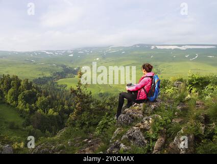 Hiker with backpack se détendre au sommet d'une montagne et profiter de la vallée durant le lever du soleil Banque D'Images