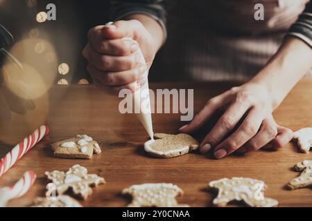 Noël, préparation de la nourriture du nouvel an. Noël pain d'épice cuisine, fabrication et décoration de biscuits fraîchement cuits. Gros plan sur une photo courte avec les mains d'une femme Banque D'Images