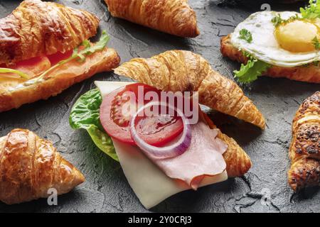 Assortiment de croissants. Divers croissants farcis sur un fond d'ardoise noire. Rouleaux remplis de jambon, saumon, oeuf, etc., photographie de nourriture, nourriture Banque D'Images