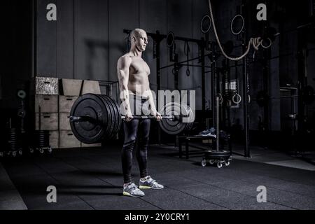 Homme musclé faisant un exercice lourd Deadlift. Gradation des couleurs spectaculaire Banque D'Images