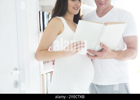 Jeune et Jolie femme enceinte livre de lecture à l'intérieur. La grossesse et la notion de famille Banque D'Images